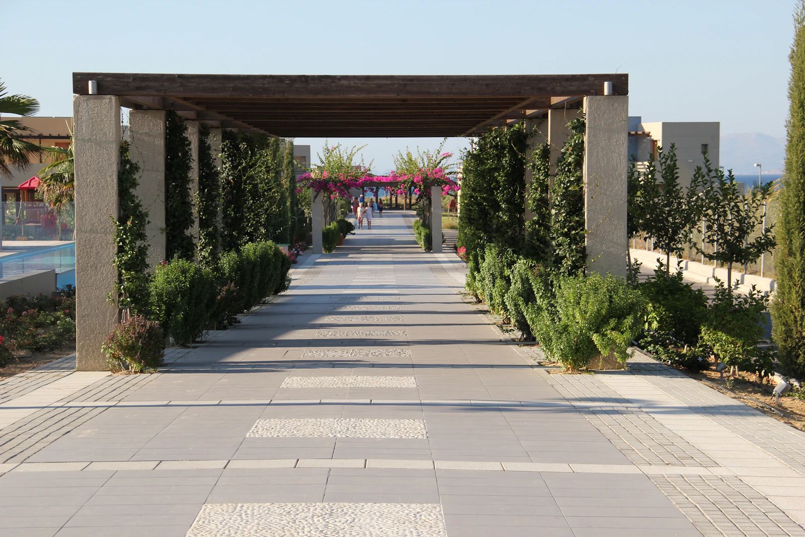 Aggregate-textured outdoor commercial pool deck walkway in a Philippine resort, wet surface with tropical landscaping